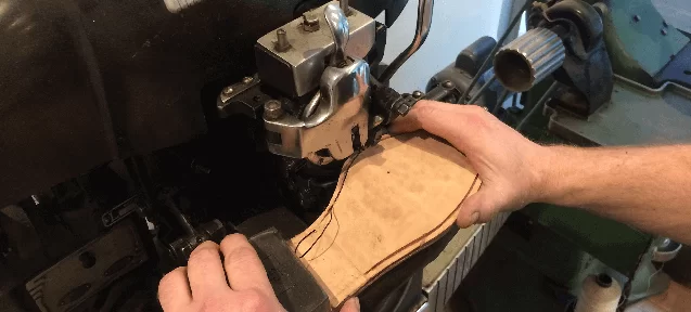 A leather sole being trimmed on the finishing machine