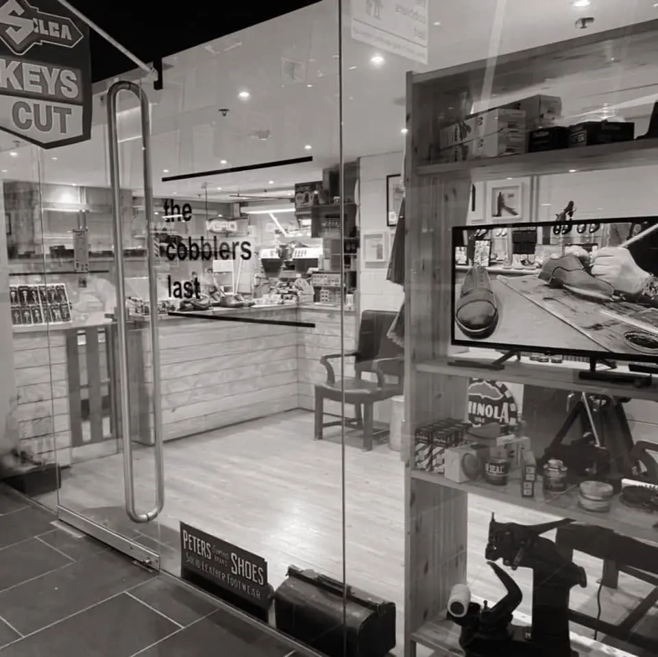 The glass shopfront at night with the cobblers last lettering and the keys cut sign