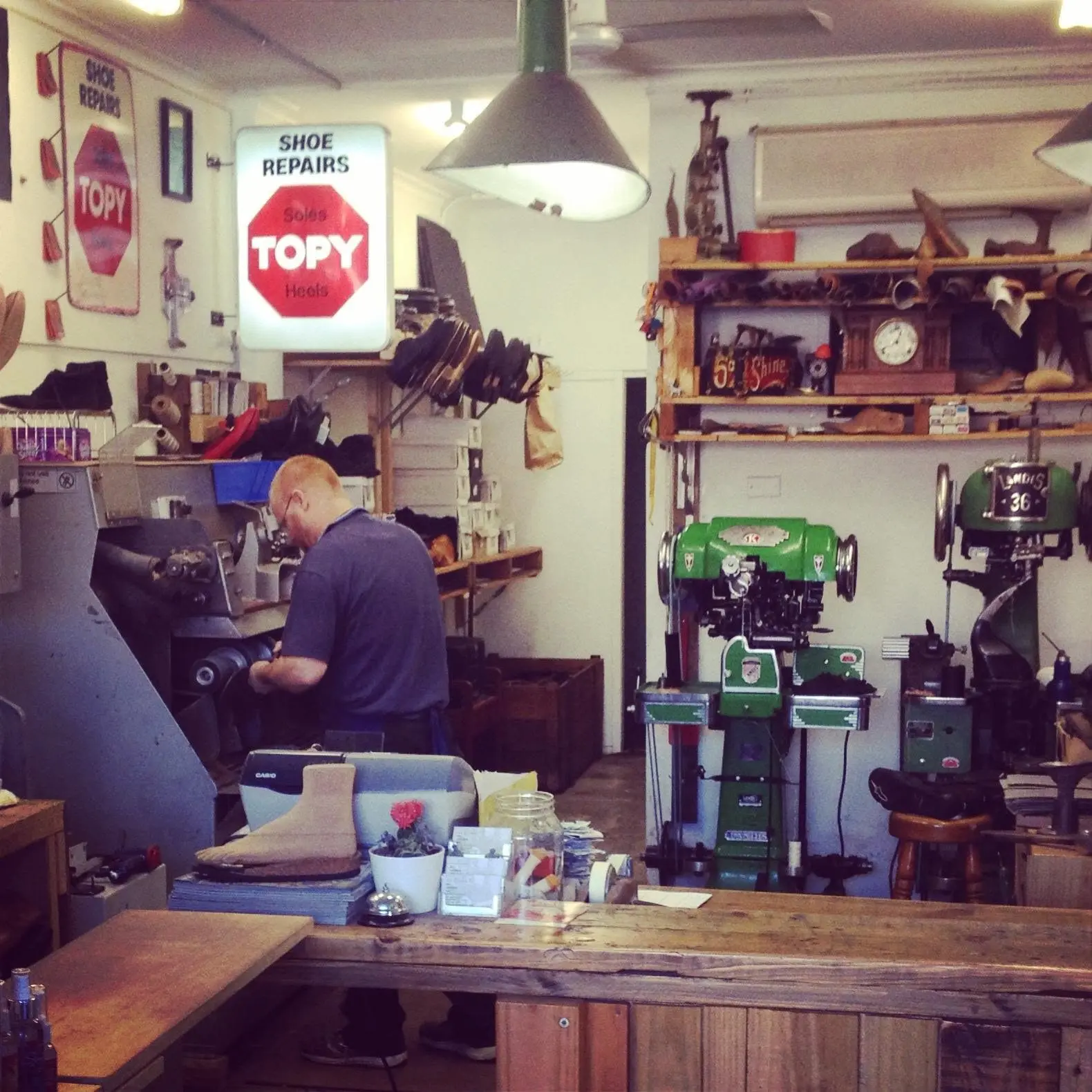 The workshop bench with the Topy shoe repairs sign and green Landis 36 stitching machines
